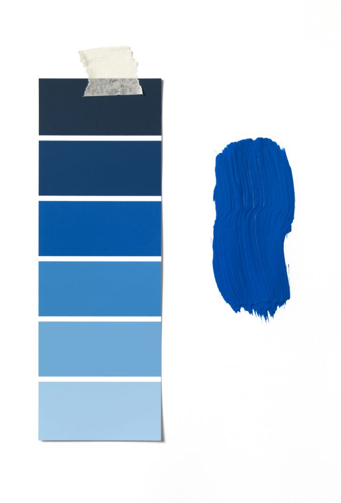 Blue colour swatch taped to wall next to blue paint swatch